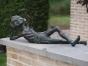 Bronzeskulptur Liegender Kobold auf Steinmauer im Garten