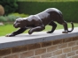 Bronzeskulptur Panther schleichend auf einer Steinmauer
