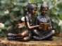 Bronzeskulptur Sitzendes Kinderpaar mit brauner Patina und Ihrem Buch auf einem Baumstamm 