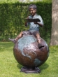Bronzeskulptur Junge sitzend auf einem Globus im Garten 