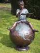 Bronzeskulptur Sitzender Kleiner Junge auf einem Globus mit braun grüner Patina 