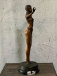 Stehende Frau aus Bronze von der Seite auf einem Marmorsockel 