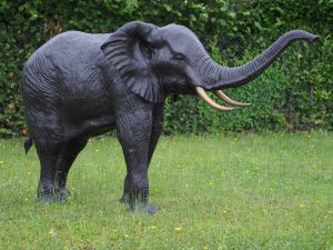 Bronzeskulptur "Lebensgrosser Elefant" mit einer braunen Patina stehend im Garten