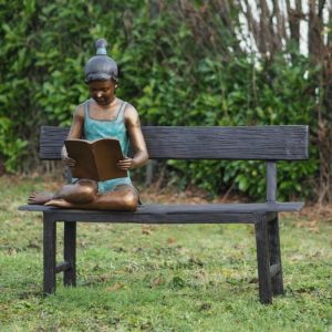 Bronzeskulptur "Marie mit Buch auf Bank" auf einer Wiese
