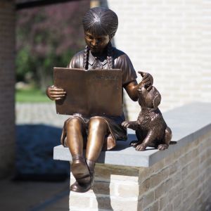 Bronzefigur Wilma mit Hund und mit Buch auf Mauer
