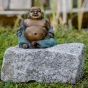 Bronzeskulptur "Happy Buddha" von vorne auf einem Stein