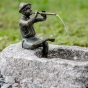 Bronzeskulptur "Flötenspieler Finn" als Wasserspeier auf einem Stein von der Seite