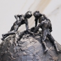 Skulptur von 3 Personen auf Weltkugel