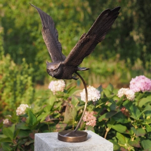 Bronzeskulptur Fliegende Eule auf Sockel mit brauner Patina im Garten