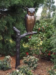 Bronzeskulptur Eule sitzend auf einem Baumfragment mit brauner Patina im Garten