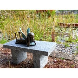 Liegende Fee aus Bronze auf Steinbank am Teich