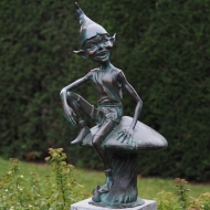 Bronzefigur Gnom auf Pilz im Garten
