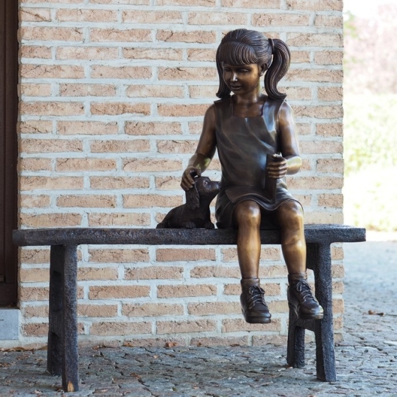 Bronzeskulptur "Annika streichelt ihren Welpen auf Bank"