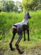 Bronzeskulptur Stehender Dobermann in einem Feld von hinten