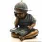  Bronzefigur "Der kleine Junge Tim mit Cappi ist ganz in sein Buch vertieft". Bronzefiguren und Gartenfiguren bei Kunsthandel Lohmann in Timmendorfer Strand.