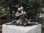 Bronzeskulptur Liebespaar sitzend auf einer Säule im Garten mit brauner Patina 