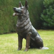 Bronzeskulptur Sitzender Schäferhund Rex mit einer braunen Patina im Garten 