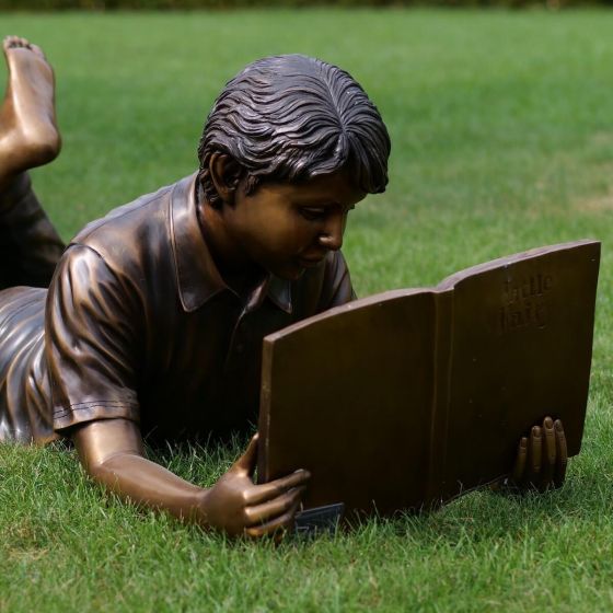 Bronzeskulptur liegender Junge Fritz mit seinem Buch 