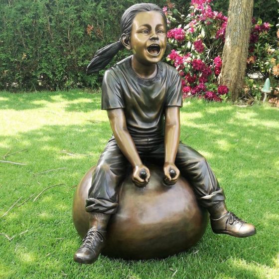 Bronzeskulptur Nele mit Ihrem Hüpfball im Garten 