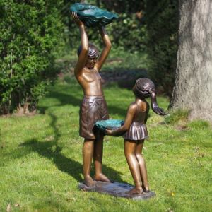 Bronzefigur zweier Kinder mit Schalen in Muschelform als Wasserspiel im Garten.