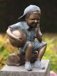 Bronzeskulptur Kleiner Junge sitzend auf einem Holzstamm im Garten 